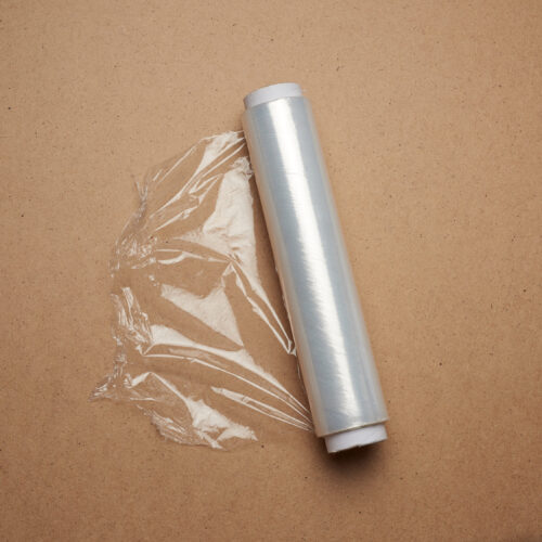big roll of wound white transparent film for wrapping food big roll of wound white transparent film for wrapping food, brown wooden background, top view