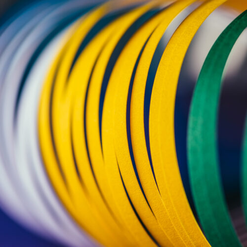 close up of white, green and yellow quilling paper curves on blue close up of white, green and yellow quilling paper curves on blue